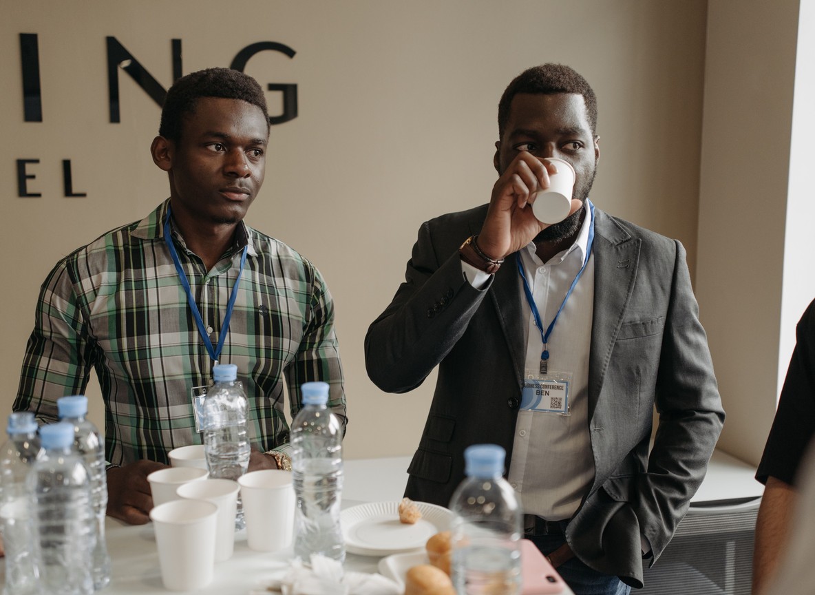 Business conference delegates with lanyards networking over coffee between summit sessions