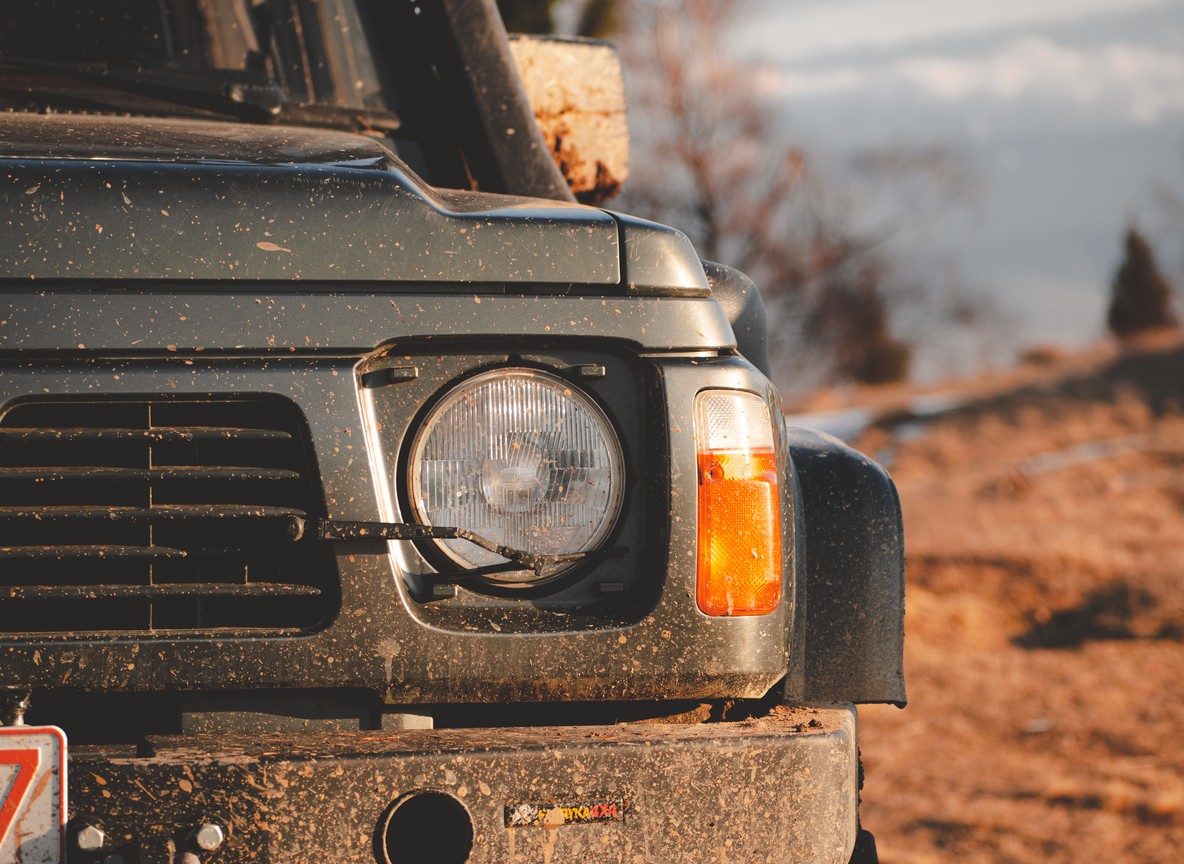 Safari 4x4 vehicle on a dirt track crossing a wide dry savanna landscape in Tsavo West National Park