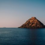 Volcanic Central Island rising from the jade waters of Lake Turkana, its crater rim visible from a fishing boat approaching from Loiyangalani
