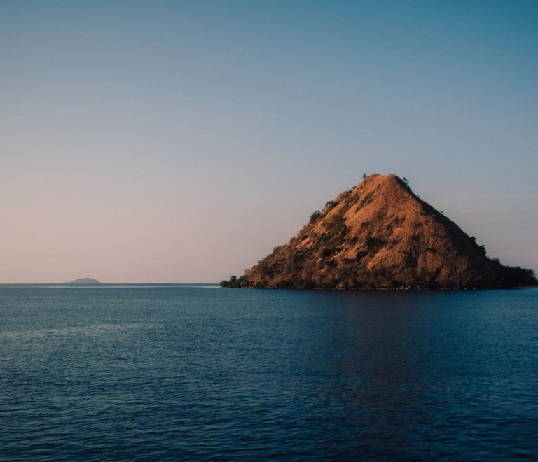 Volcanic Central Island rising from the jade waters of Lake Turkana, its crater rim visible from a fishing boat approaching from Loiyangalani