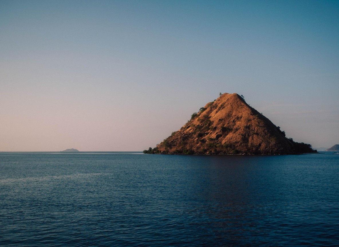 Volcanic Central Island rising from the jade waters of Lake Turkana, its crater rim visible from a fishing boat approaching from Loiyangalani