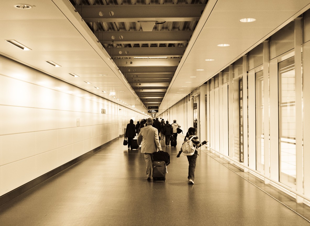 arrivals hall at an international airport terminal with travelers and luggage, morning light