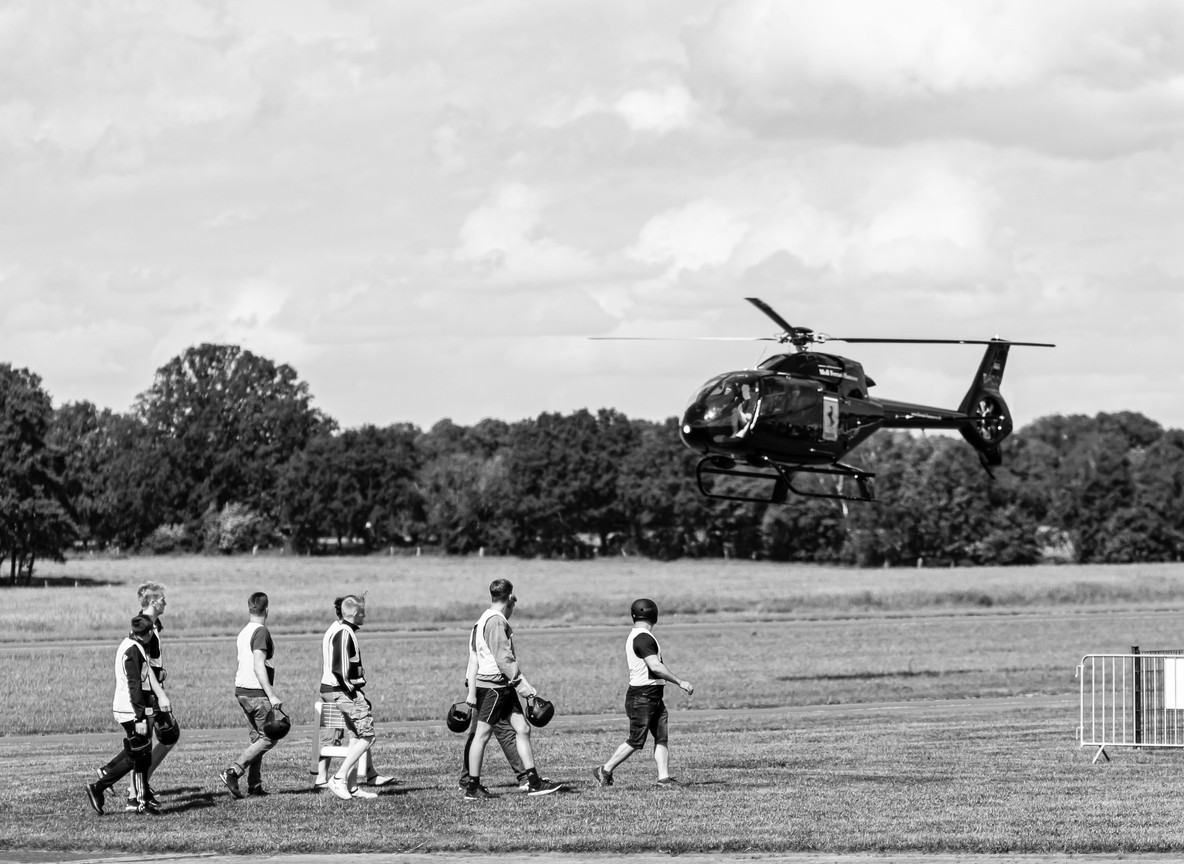 A small charter helicopter landing on open grass with passengers approaching, illustrative of a private safari transfer