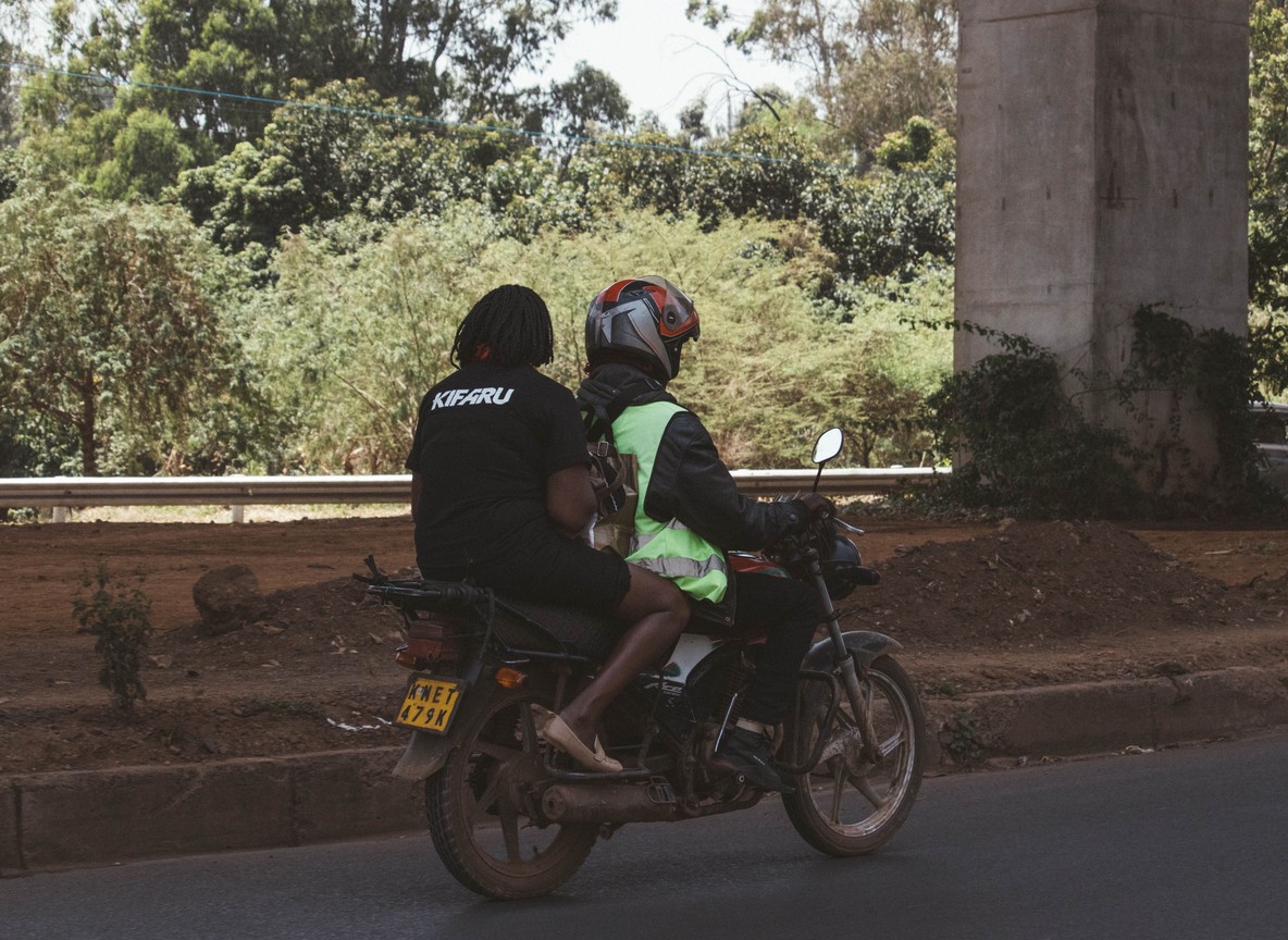 a solo woman traveler with a daypack walking confidently through a quiet, leafy Nairobi neighborhood street in daylight