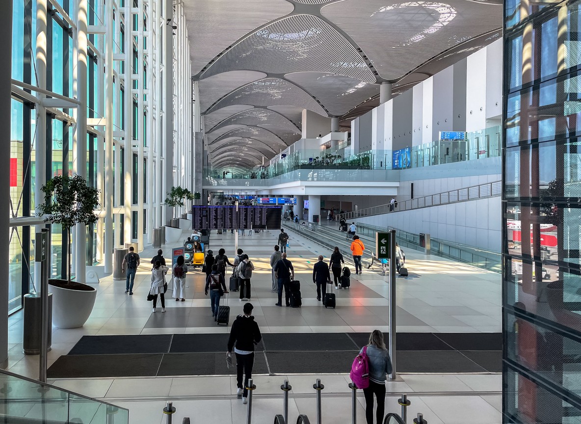 Travelers moving through a bright, modern airport concourse, the scale and design a preview of what JKIA's new terminal is built to deliver