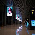 International airport departures hall with digital signage and travelers walking through the terminal