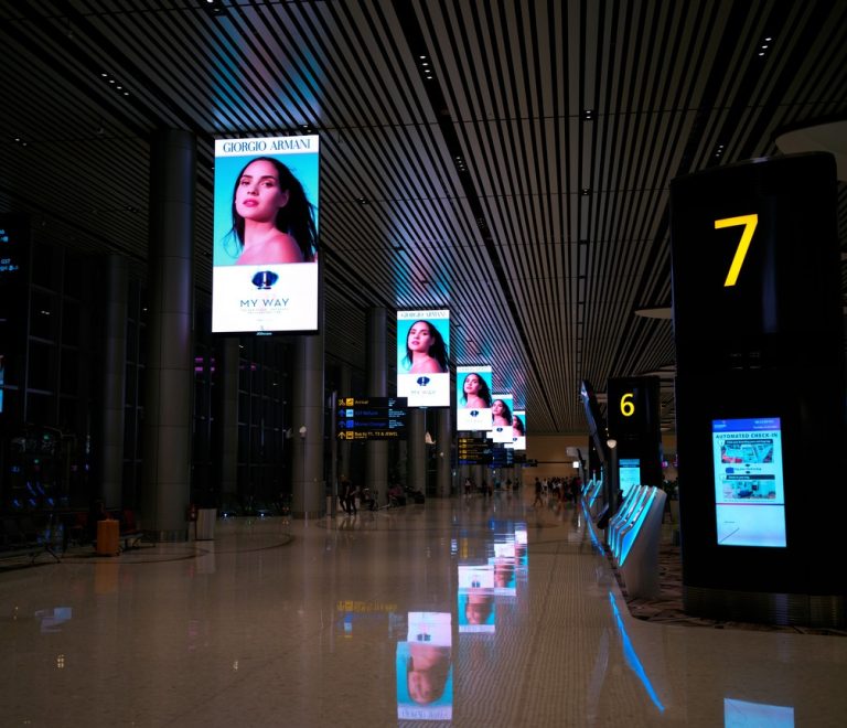 International airport departures hall with digital signage and travelers walking through the terminal