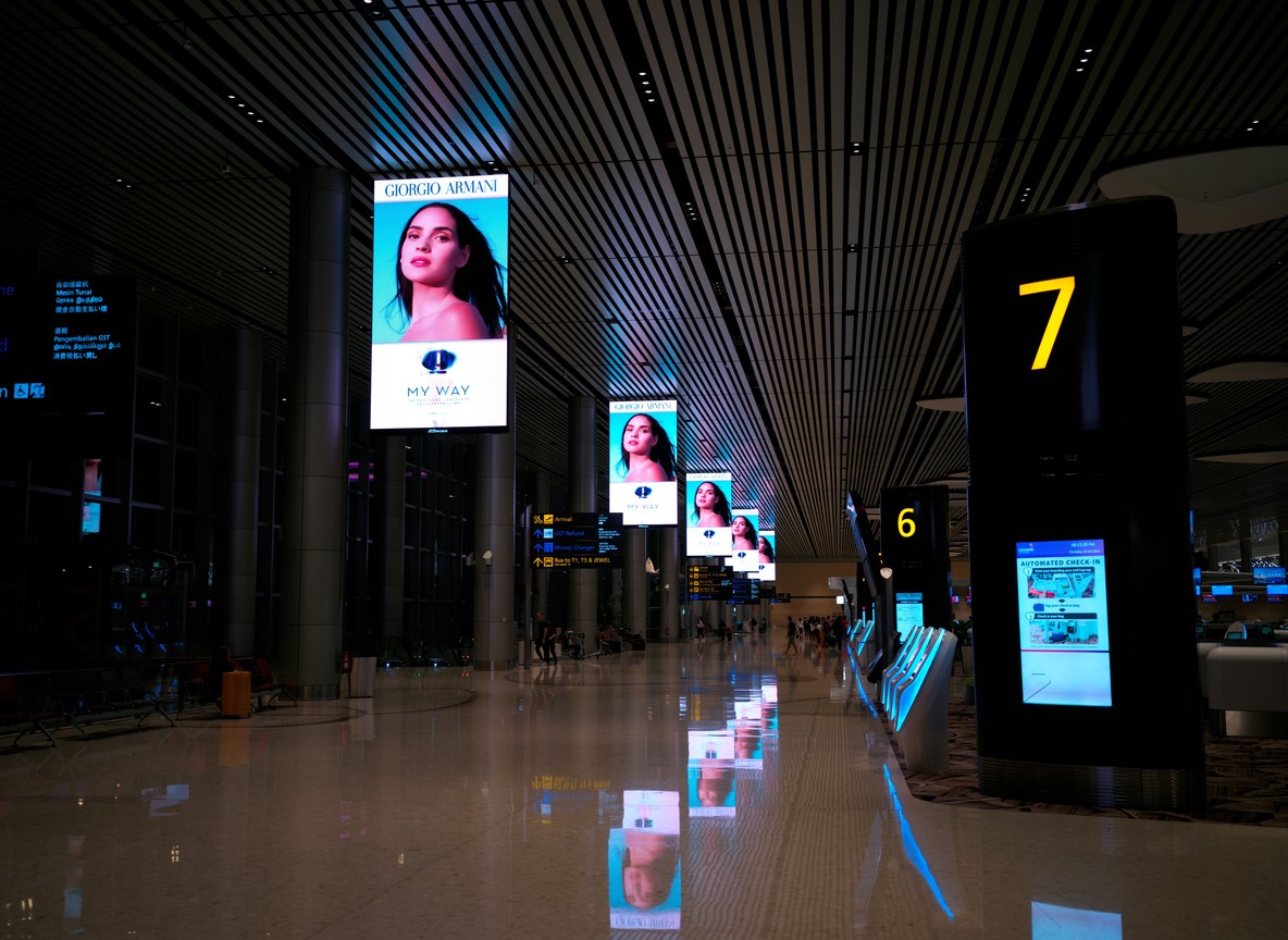 International airport departures hall with digital signage and travelers walking through the terminal