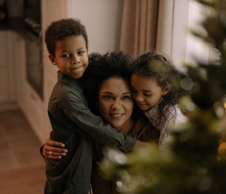 a mother embracing her two children in a warm family homecoming hug