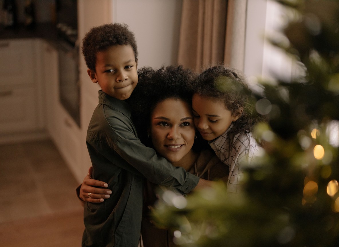 a mother embracing her two children in a warm family homecoming hug