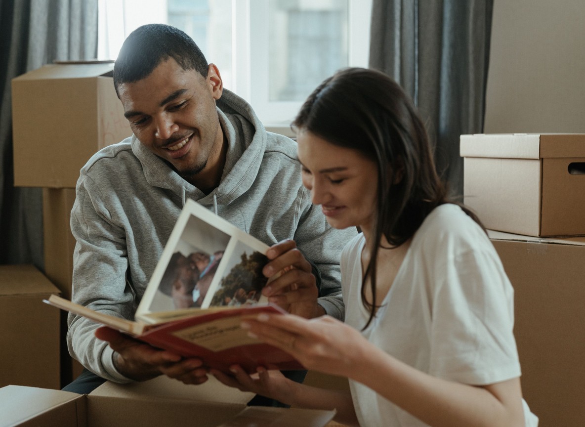 a couple smiling together while paging through an old family photo album