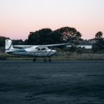 A small single-engine aircraft parked on an airstrip apron at dusk, the kind of light aircraft used on Kenya's scheduled safari flight network