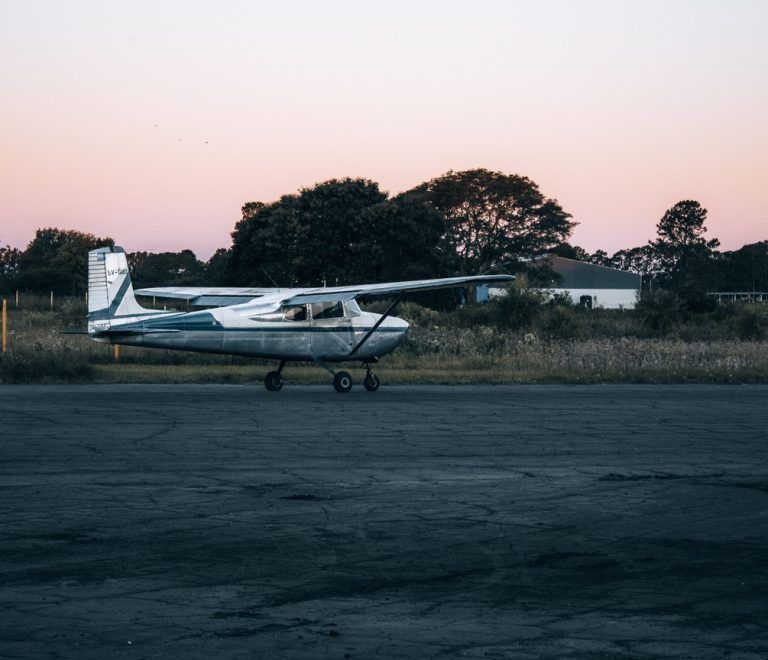 A small single-engine aircraft parked on an airstrip apron at dusk, the kind of light aircraft used on Kenya's scheduled safari flight network