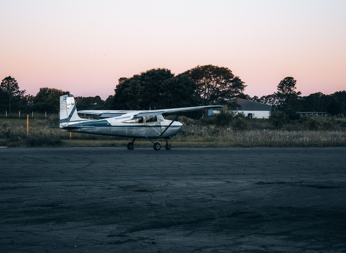 A small single-engine aircraft parked on an airstrip apron at dusk, the kind of light aircraft used on Kenya's scheduled safari flight network