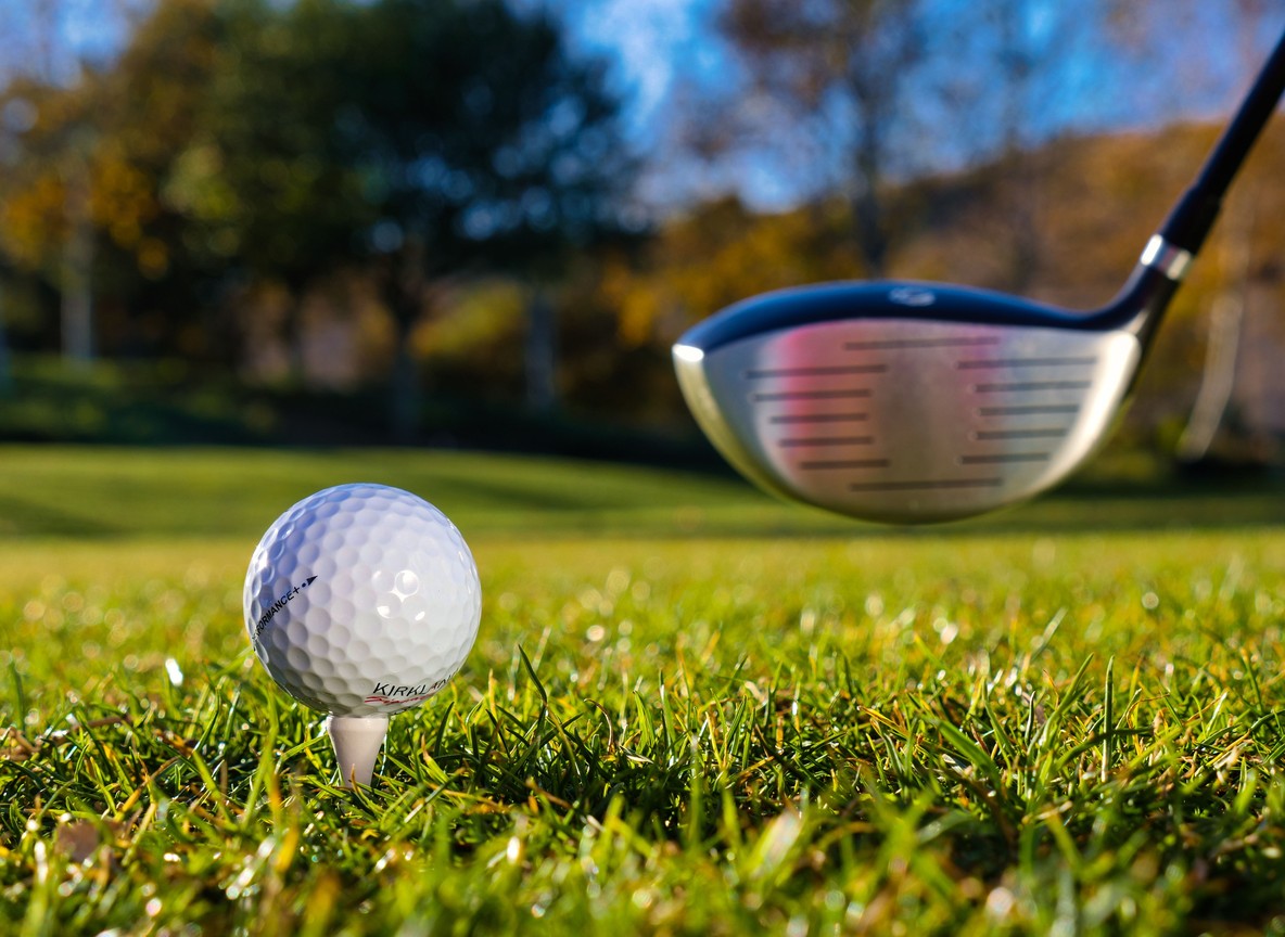 Close-up of a golf ball on a tee with a driver mid-swing, representing the tee-off experience travelers can expect at Kenya's coastal courses