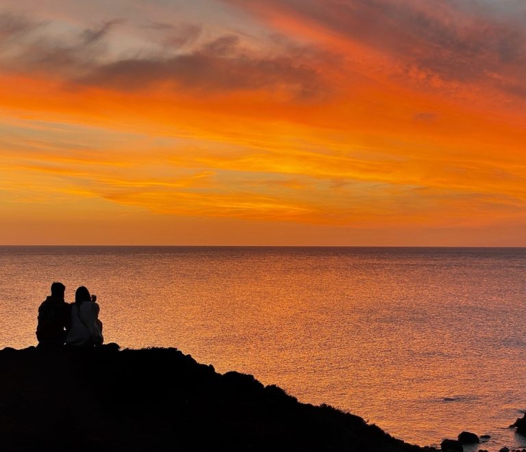 A couple watching a golden sunset from a safari vehicle overlooking the Masai Mara plains