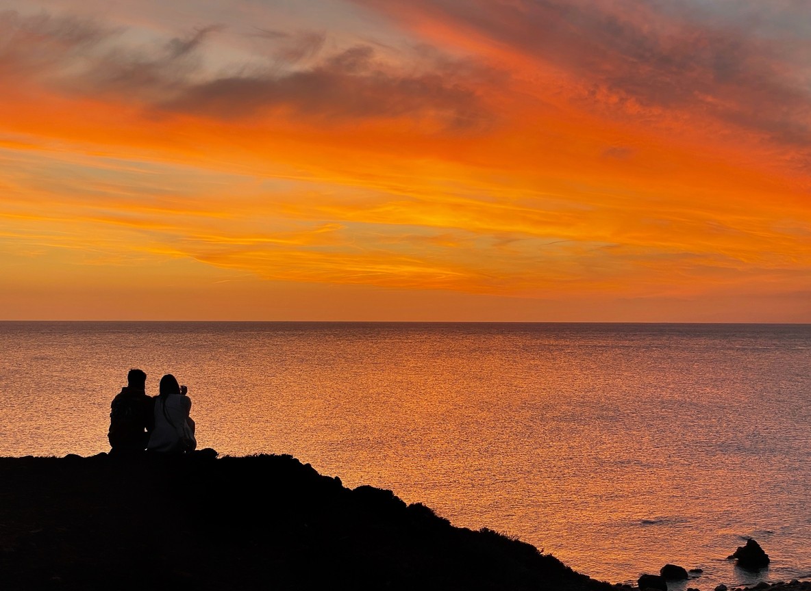 A couple watching a golden sunset from a safari vehicle overlooking the Masai Mara plains
