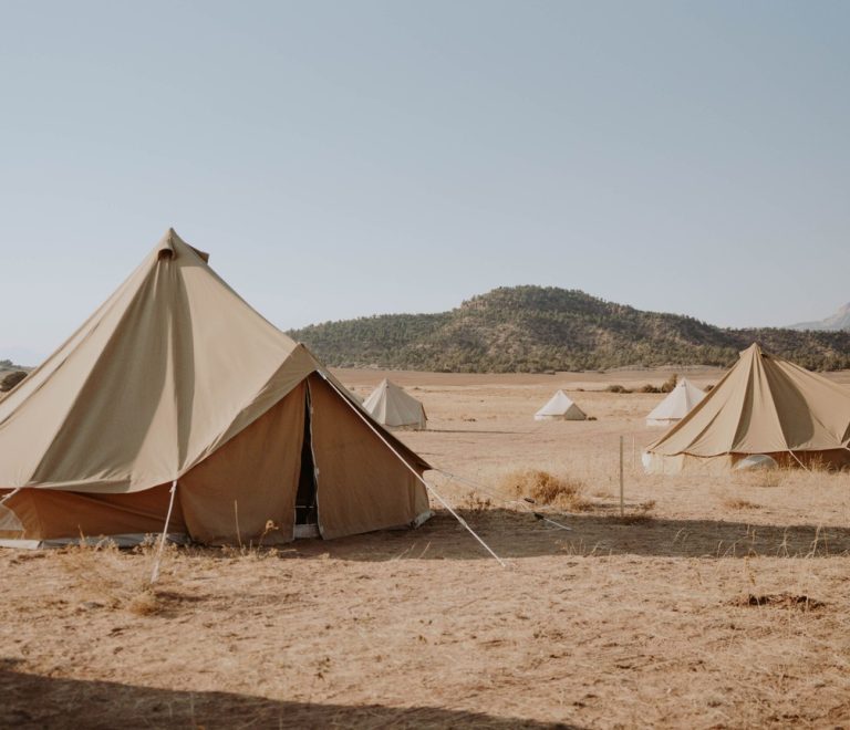 folded safari clothing and a laundry basket on a tent veranda, warm afternoon light