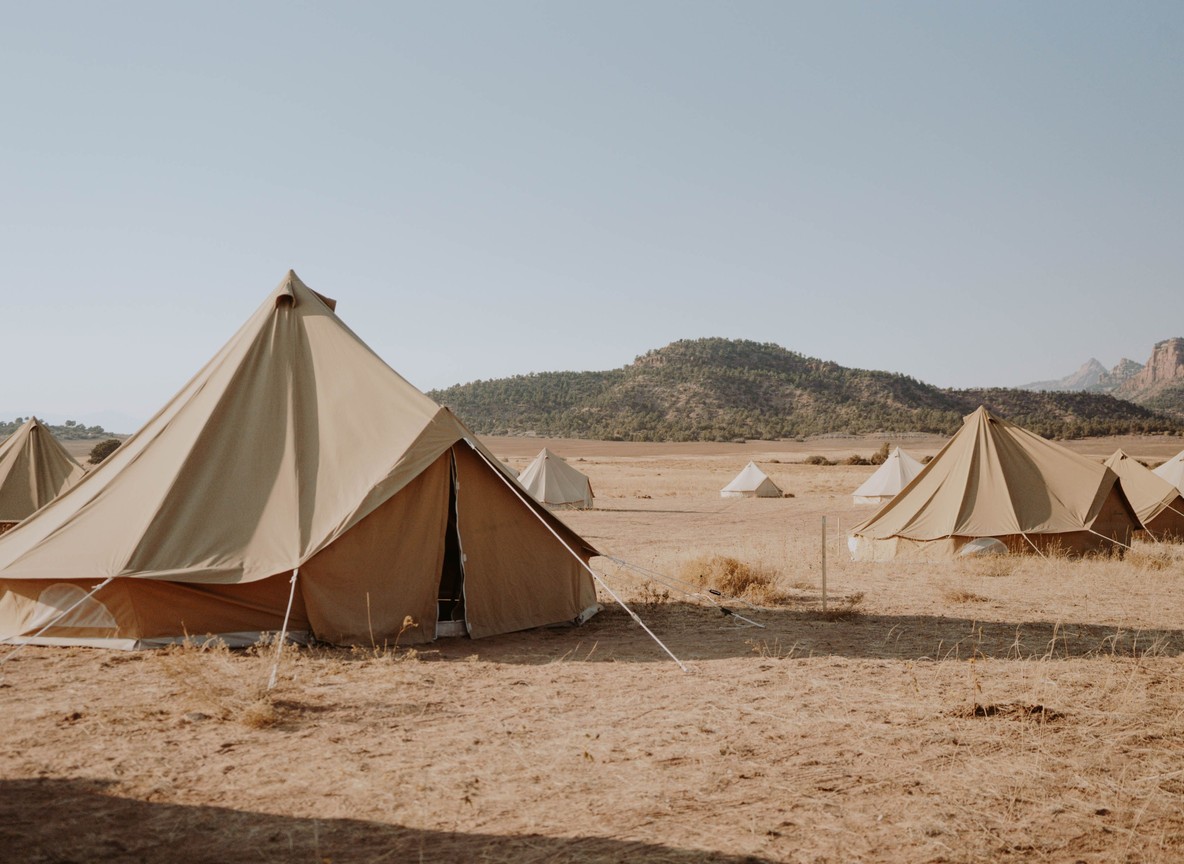 folded safari clothing and a laundry basket on a tent veranda, warm afternoon light