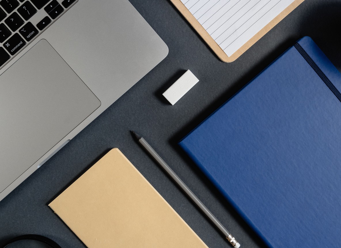 a flat-lay desk scene with a laptop, notebooks, and pen used for building a day-by-day safari itinerary