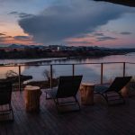 a safari lodge deck with loungers overlooking a river at sunset in Kenya