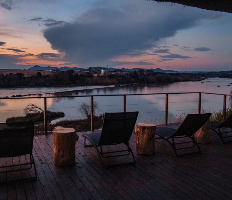 a safari lodge deck with loungers overlooking a river at sunset in Kenya