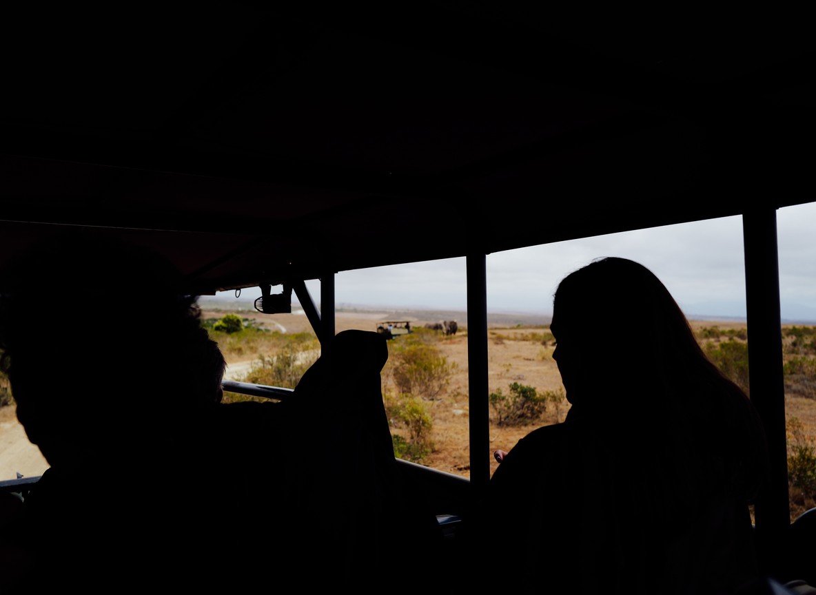 A single open safari vehicle parked on an empty savannah track at golden hour with no other vehicles in sight, Laikipia hills in the background