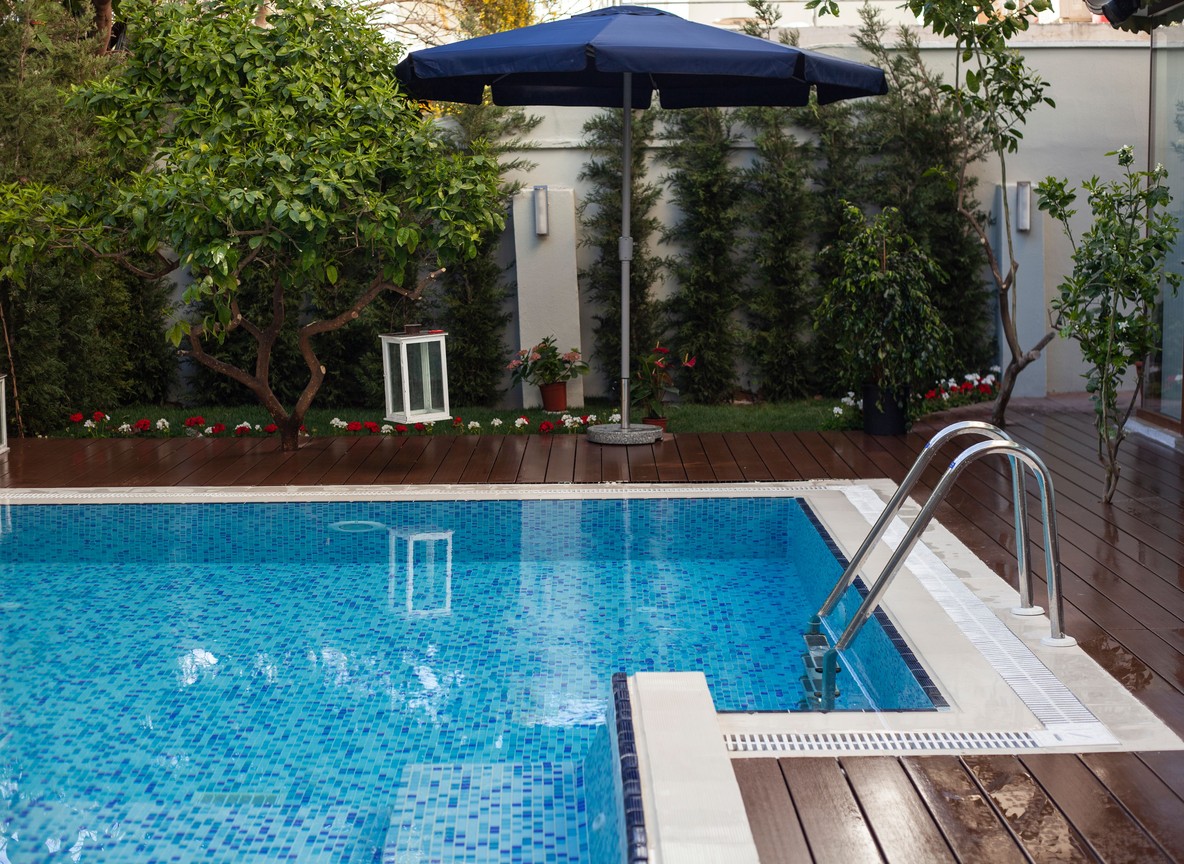 A small private plunge pool on a wooden lodge deck with shade umbrella and greenery, no people visible