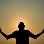 Silhouette of a figure in a yoga pose against a golden sunrise sky at a Kenya safari lodge