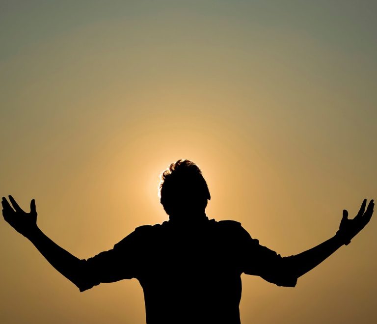 Silhouette of a figure in a yoga pose against a golden sunrise sky at a Kenya safari lodge