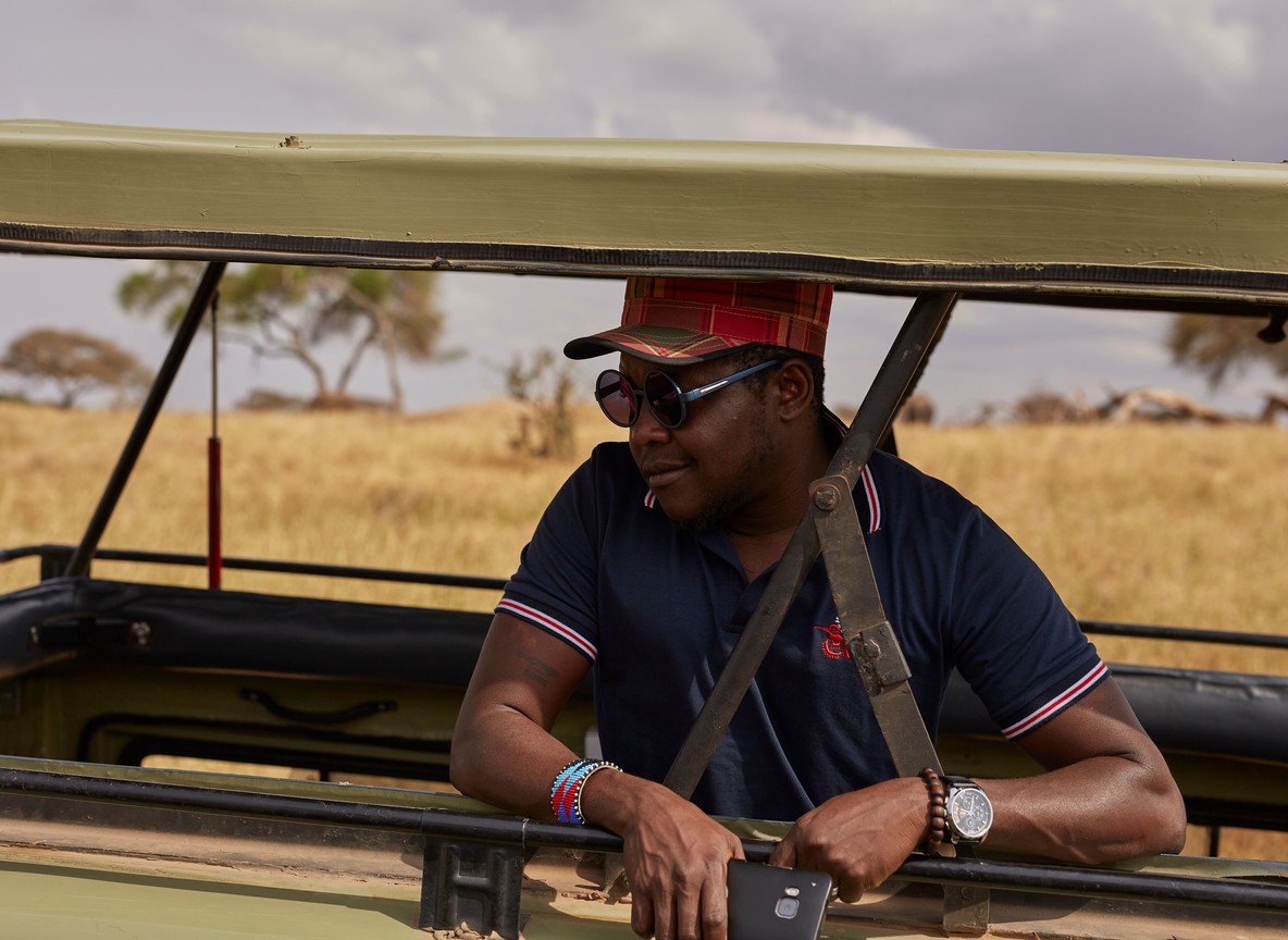 Maasai safari guide watching for wildlife from an open game-drive vehicle on the Amboseli plains