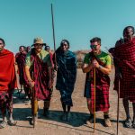 Maasai landowners and a safari guide standing together at sunrise on open grassland in a Kenyan wildlife conservancy