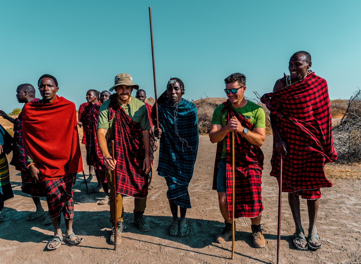 Maasai landowners and a safari guide standing together at sunrise on open grassland in a Kenyan wildlife conservancy