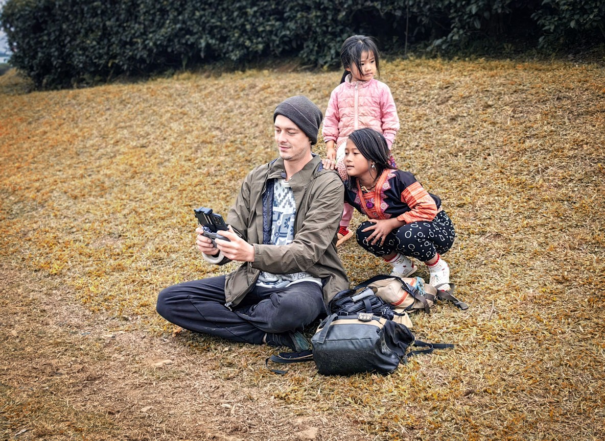 Two children looking through binoculars from a safari vehicle roof hatch in the Masai Mara