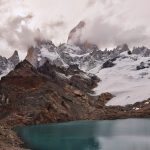 Trekkers walking a ridge trail toward Point Lenana on Mount Kenya at sunrise, with glaciated rock peaks in the background