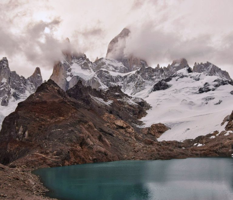 Trekkers walking a ridge trail toward Point Lenana on Mount Kenya at sunrise, with glaciated rock peaks in the background