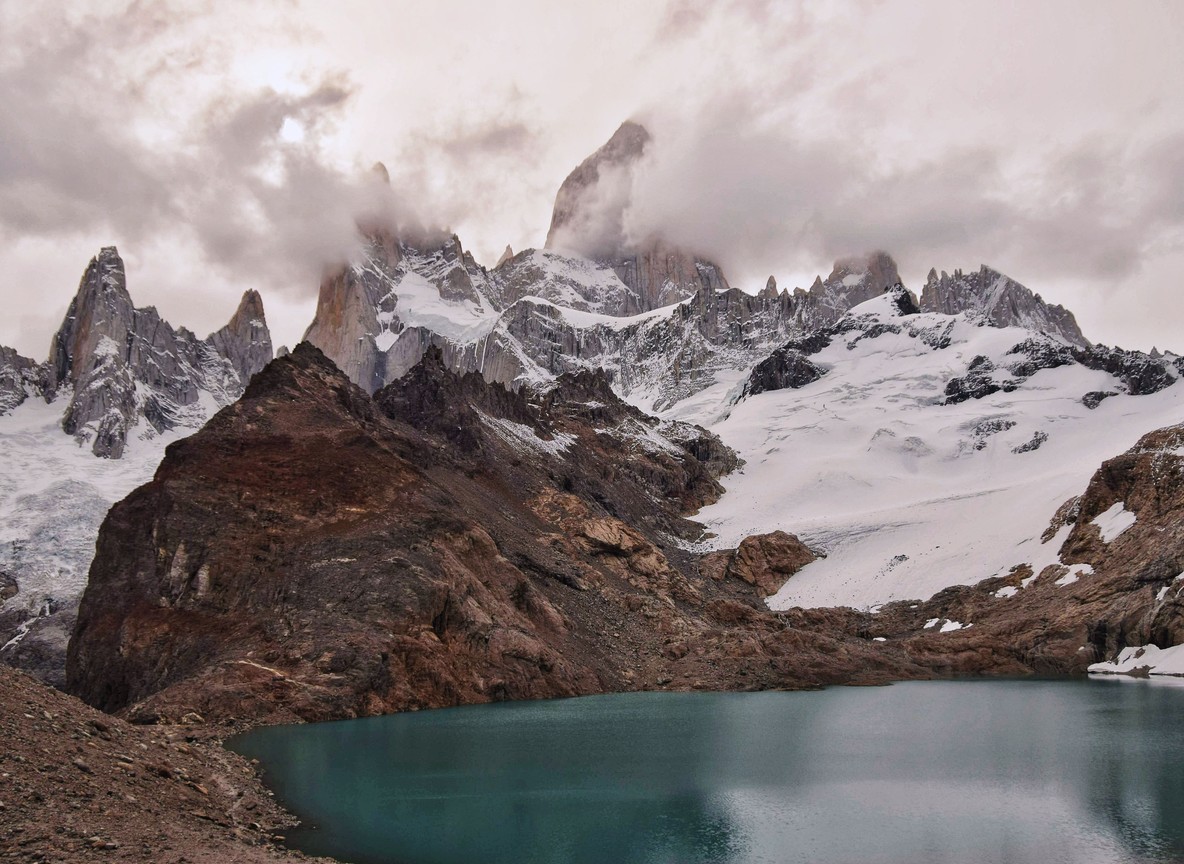 Trekkers walking a ridge trail toward Point Lenana on Mount Kenya at sunrise, with glaciated rock peaks in the background