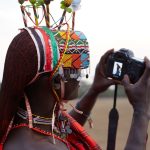 Pokot elder in traditional beaded ornaments standing in the West Pokot hills at golden hour, respectful documentary portrait